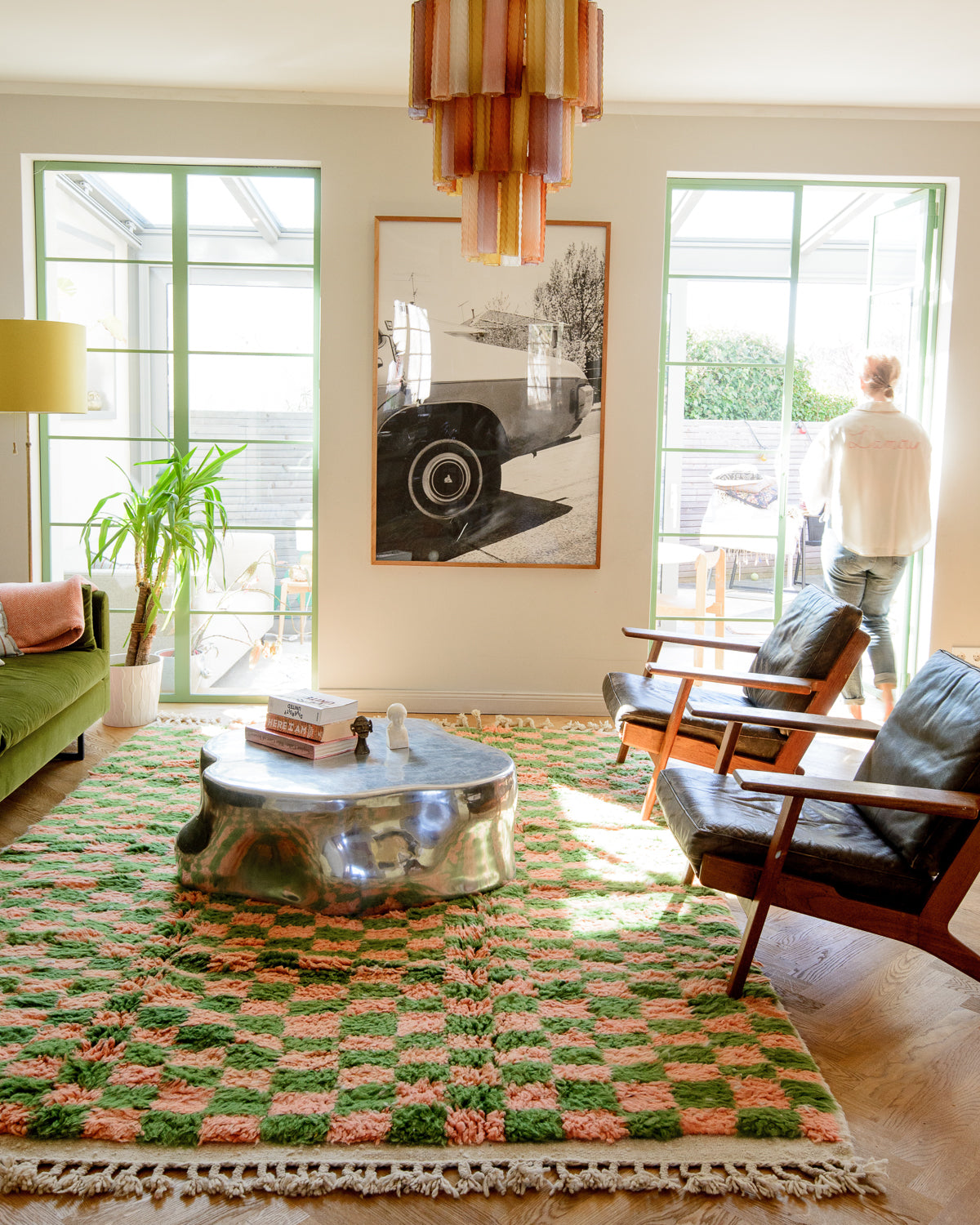Home interior with Berberlin green and coral Berber rug and mid century furniture. There is sun streaming in from outside.